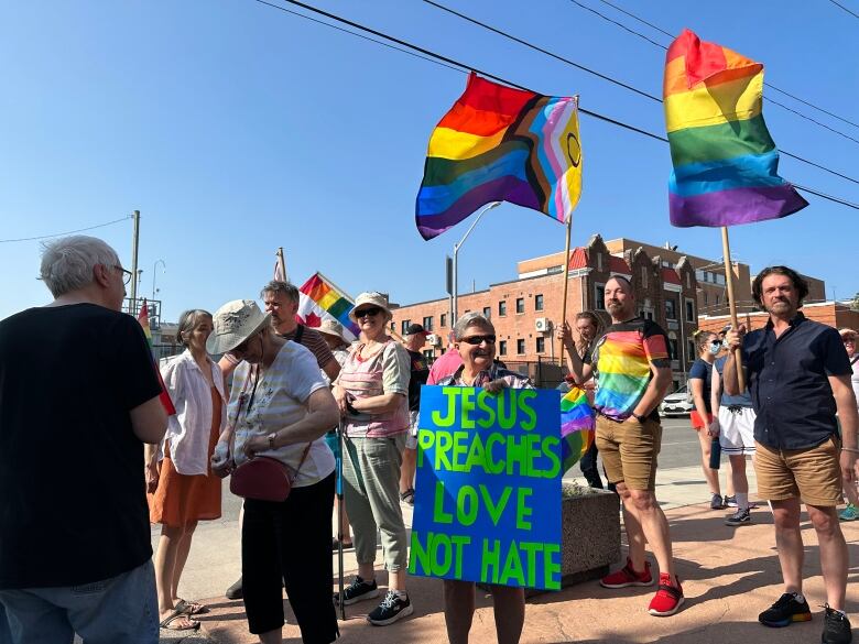 Crowds with rainbow signs and Pride flags. 