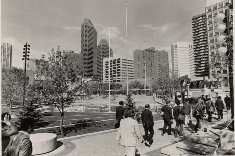 A digitized black and white photo showing people walking through an urban park