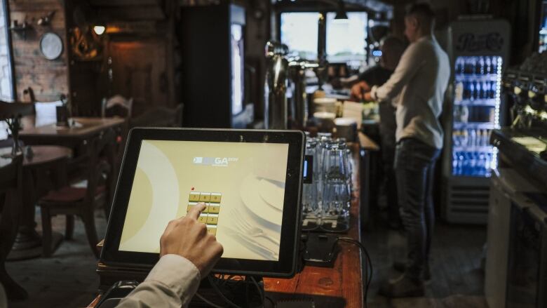 A server inputs information into a cash register system at a restaurant and bar.