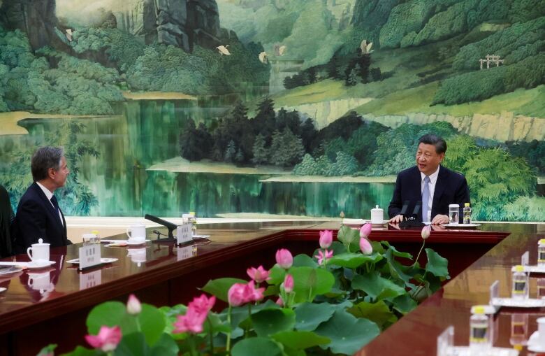 Xi sits at one end of table, Blinken seated far away, with traditional Chinese mural in background, in the Great Hall of the People in Beijing