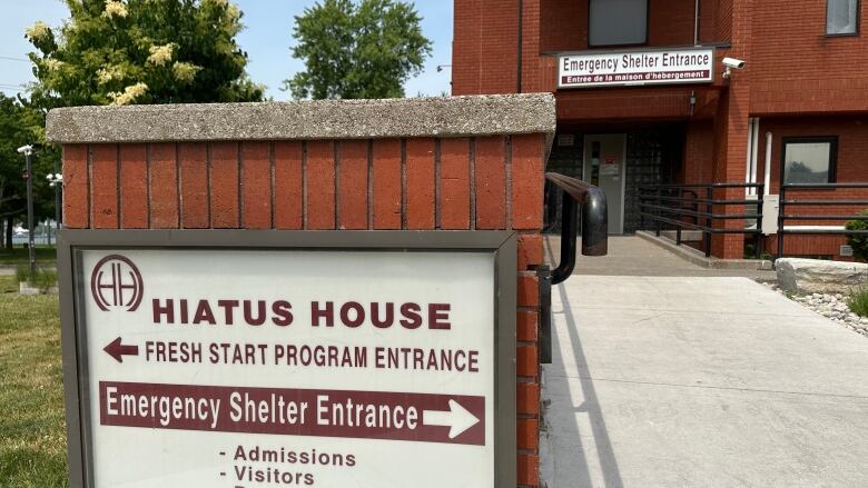 A sign reads Hiatus House outside of a red brick building. 