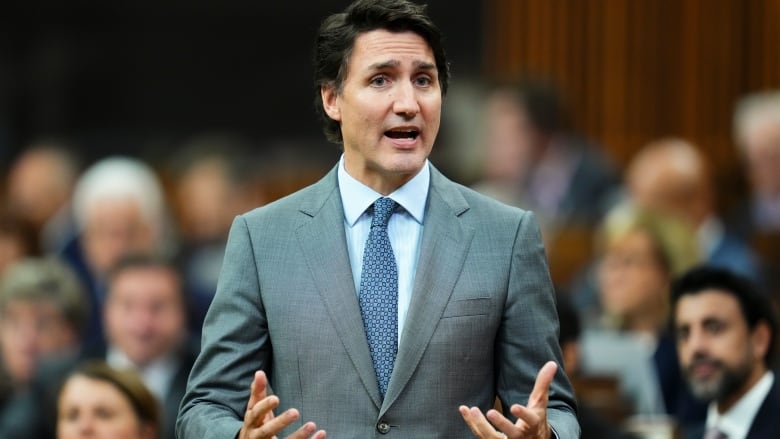 A man in a suit stands up and gestures.