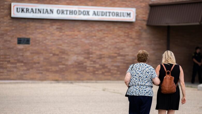 Two people walk toward a building.