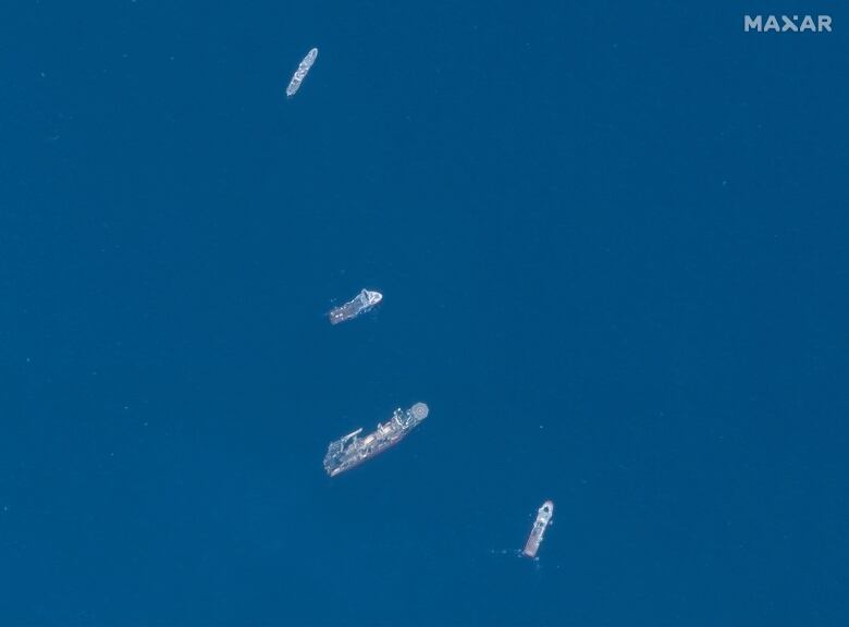 A satellite image shows ships in the ocean.