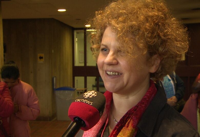 A woman with red hair speaks into a microphone. 