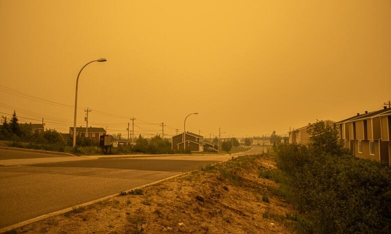 A photo of a residential neighbourhood. The photo appears to have some kind of sepia filter, but is orange due to haze and smoke in the air.