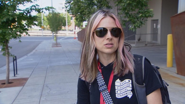 A woman is pictured wearing a t-shirt and sunglasses.