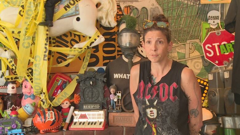 A woman in an AC/DC shirt in front of a busy background full of art.