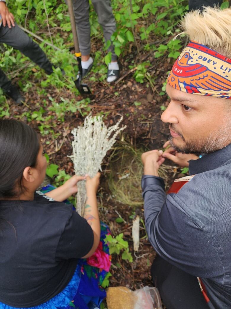 Midwifery pilot co-ordinator Anthony Johnson and doula Jodi Gadwa-Cardinal lay sage and tobacco in a hole where the placentas will be buried. 