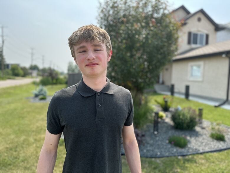 A young man stands looking into the camera lens. 