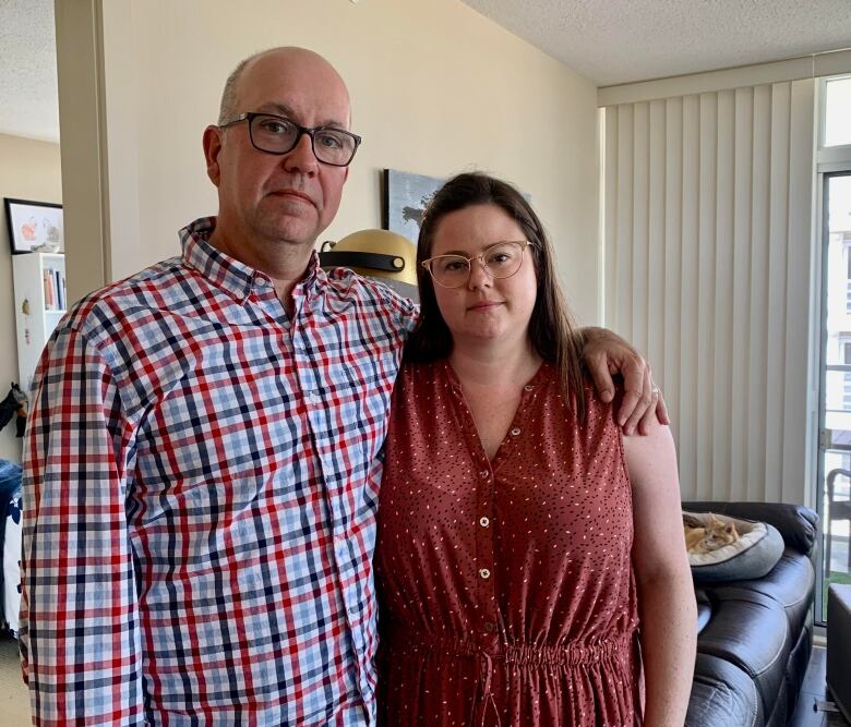 A man and woman stand in their living room.