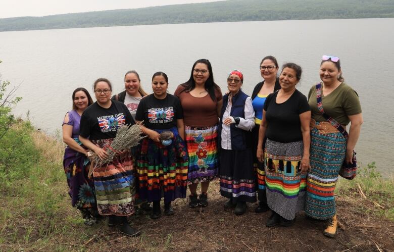 Doulas from Kehewin Cree Nation and Opaskwayak Cree Nation stand together along the shore of Lake Kehiwin. Deanna Smith (second from the left) holds sage from the ceremony. 