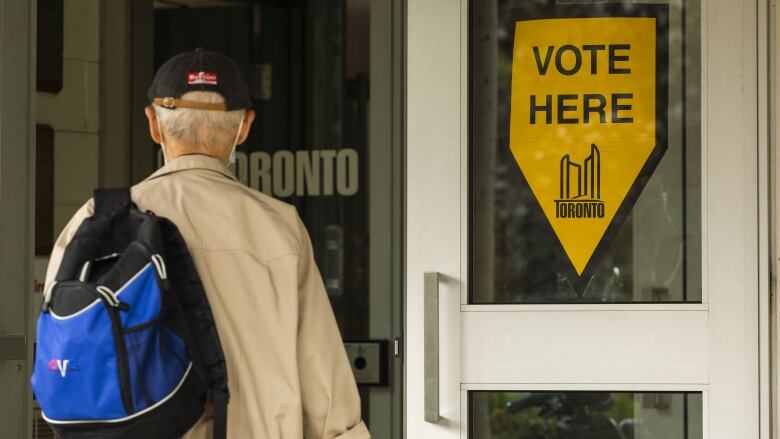 A man enters a polling station with a vote sign near him. 