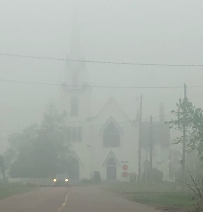 A church in Tracadie is basely visible through smoke.