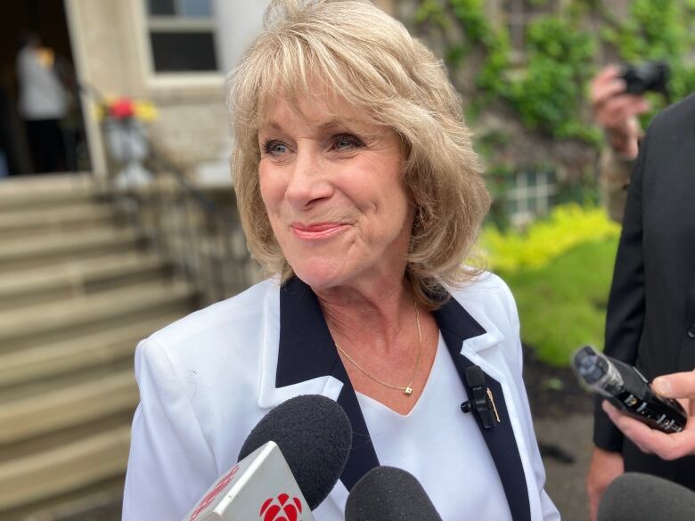 Medium shot of woman in grey suit smiling at a person off camera