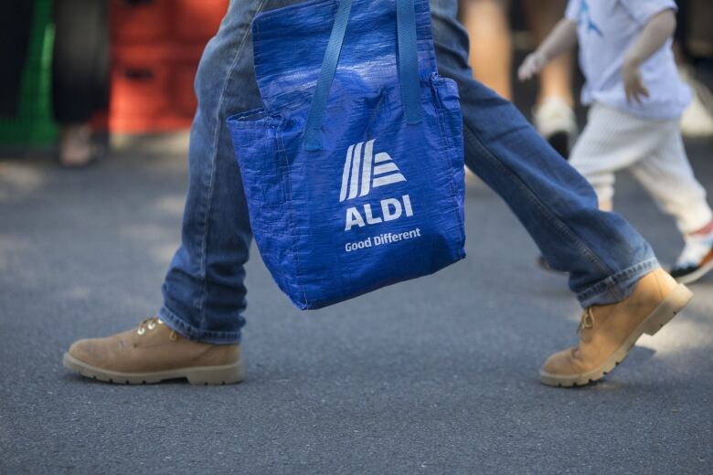 A shopper holds an Aldi shopping bag.