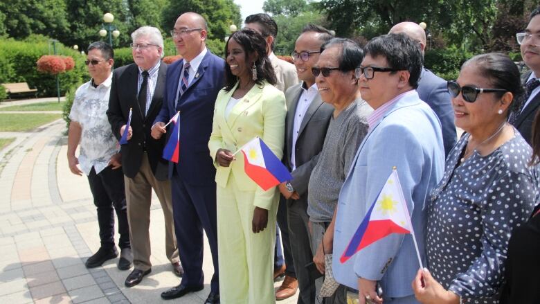 People pose for a photo, some holding flags of the Philippines. 