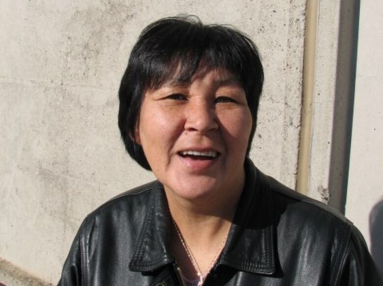 A portrait of a smiling middle-aged woman with dark hair.