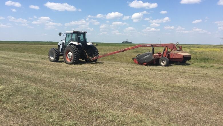 A tractor with a small baler attached 