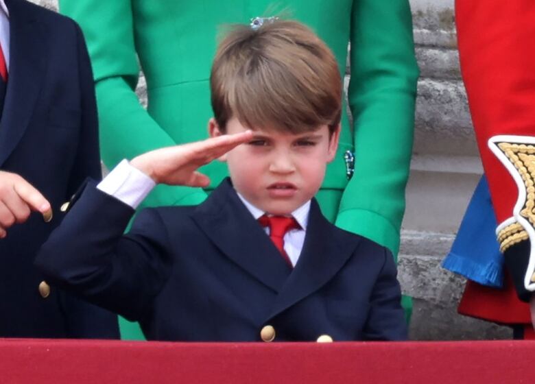 A child gives a salute while standing in front of other people.