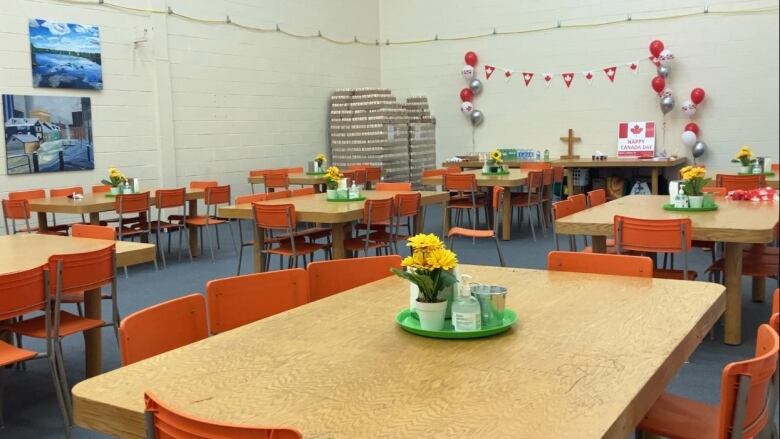 Several tables are set and decorated in an open gynasium for free meal service. 