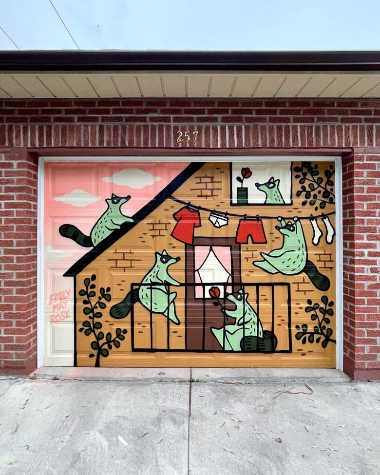 Photo of a garage door painted with a cartoon scene depicting raccoons hanging around a small balcony.