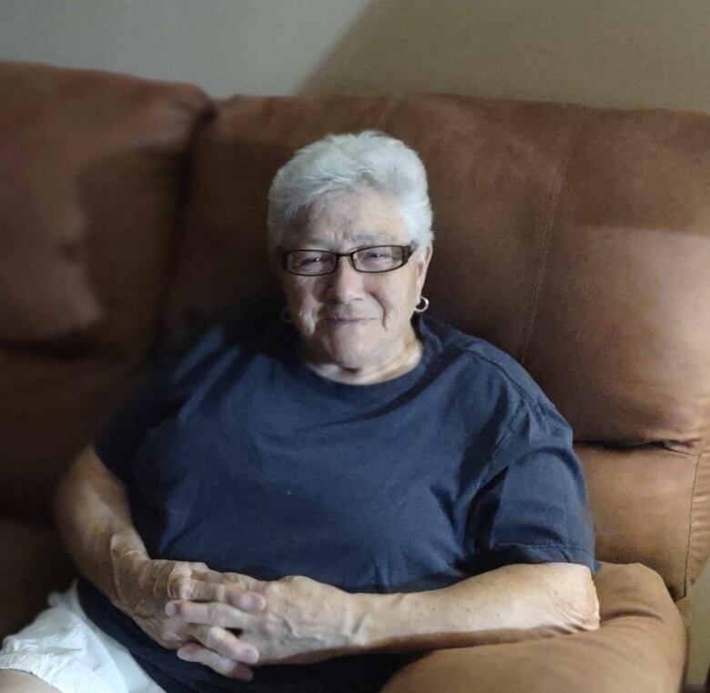 An older woman sitting on a couch.