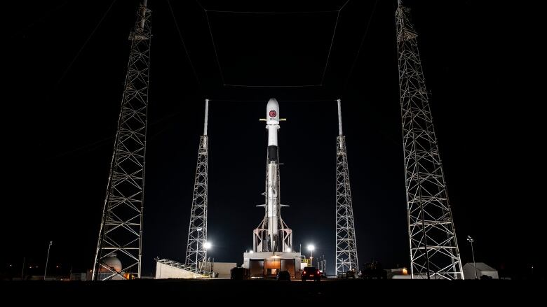 A rocket is seen on a launch pad lit by floodlights at nighttime