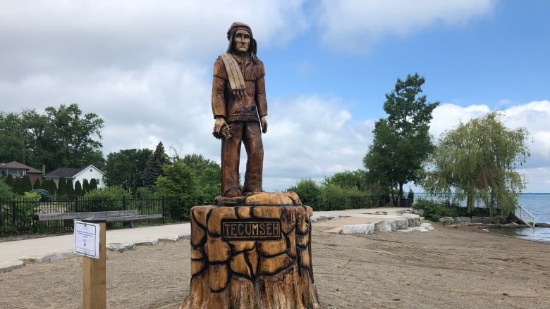 A wooden carved statue on the beach overlooking the water