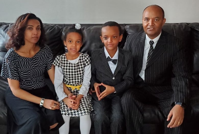 A family of four wearing formal clothes pose together for a photo. 