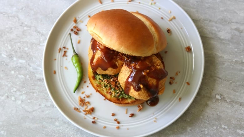 Potato fritters with ketchup, chutney, and spices on buns.