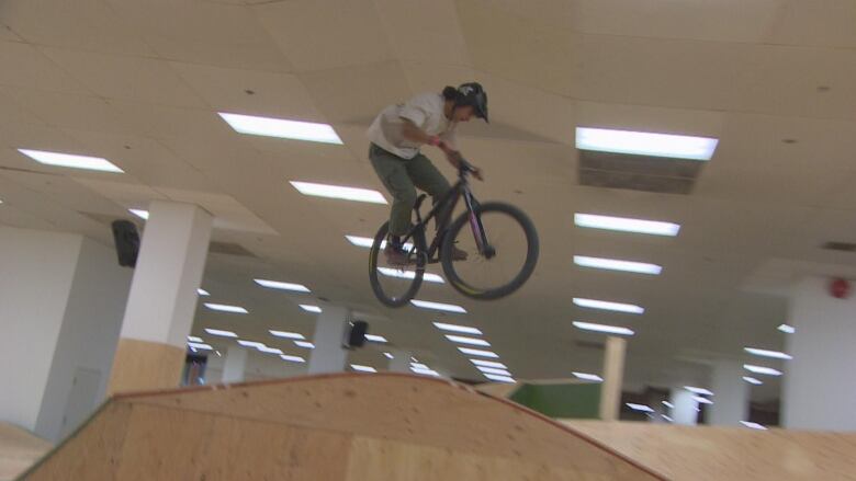 A cyclist is pictured suspended in the air doing a jump at the indoor bike park. 