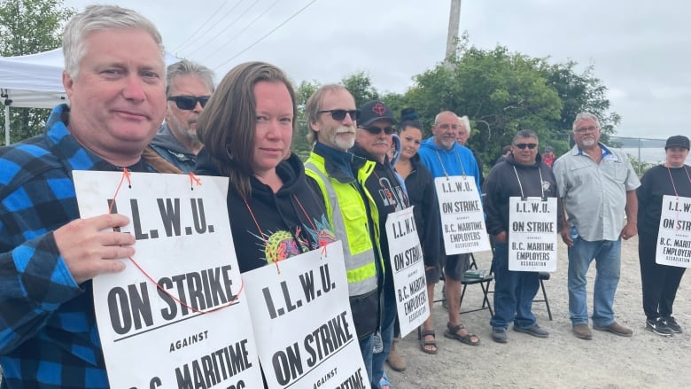 A number of people gather with signs that read 'I.L.W.U On Strike Against B.C. Maritime Employers Association'.