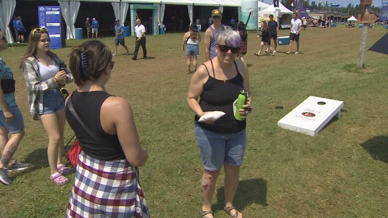 Music fans play a beanbag toss game on the music festival grounds.