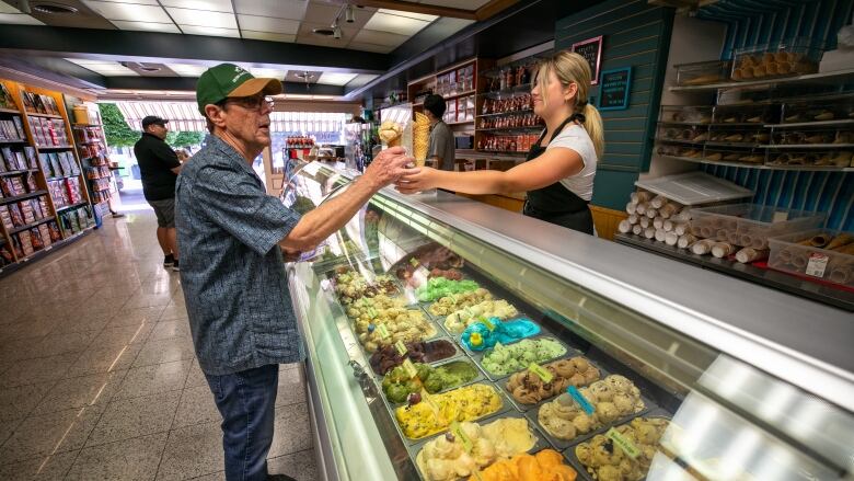 A woman hands an ice cream cone to a man.