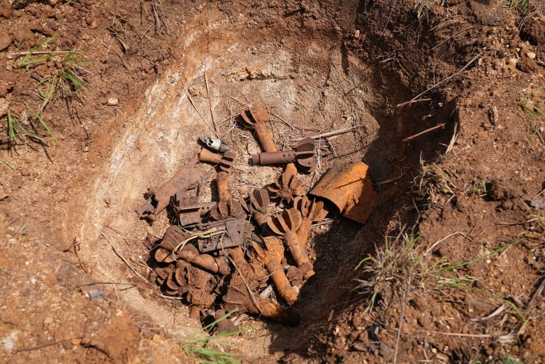 A closeup of a rock in the dirt shows what appears to be small munitions.