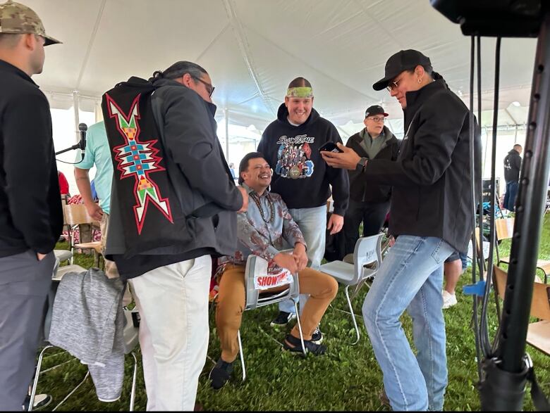 A group of men stand together underneath a white tent.