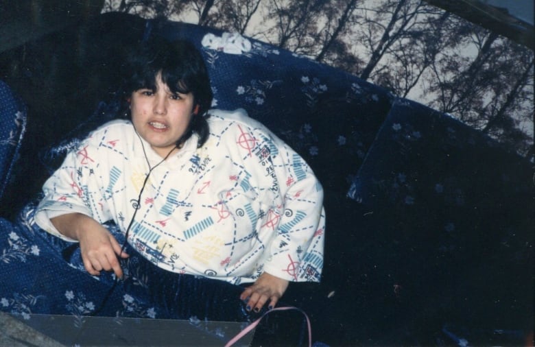 A woman is sitting on a large couch. 