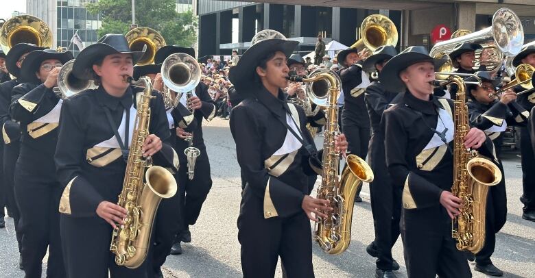 a marching band dressed in black an gold uniforms performs on a Calgary street.