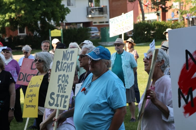 A crowd of people holding protest signs, one reading 