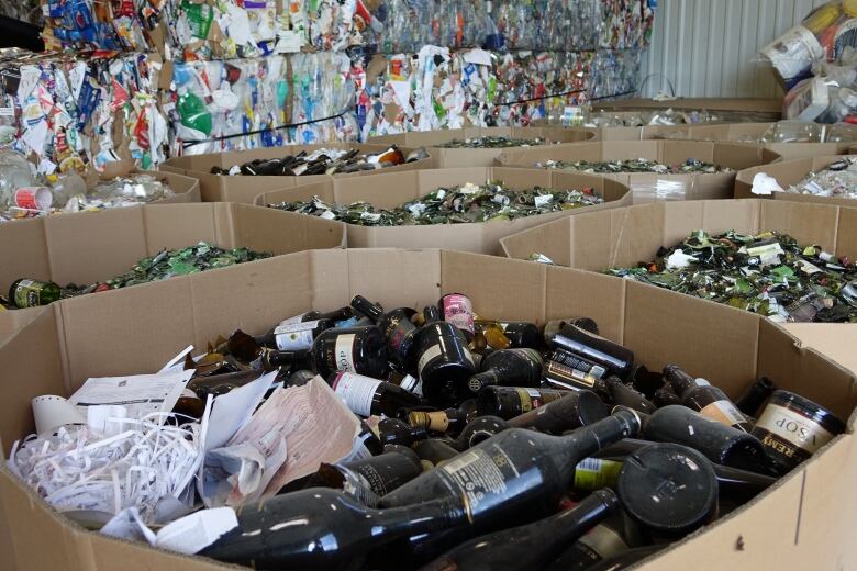 Bins filled with broken glass bottles and recycling packages behind them.