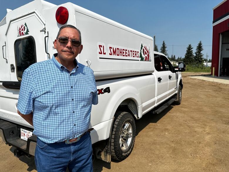 A man stands in front of a white truck.