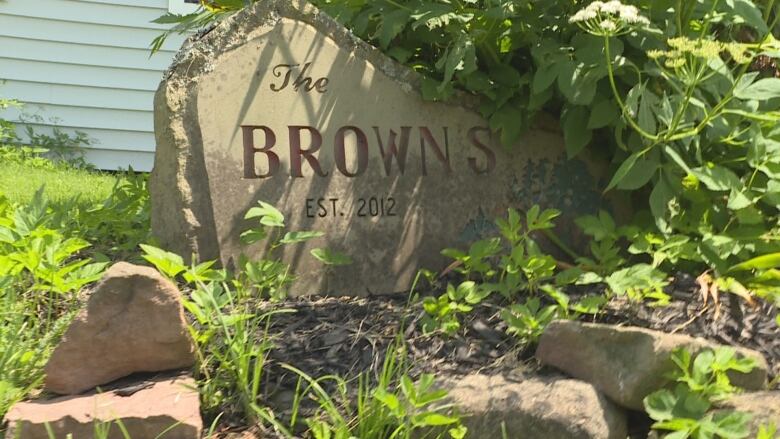 A large rock covered by shrubs with te name The Browns engraved on it.