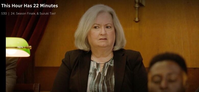 A women with light grey hair has a stern look on her face. 