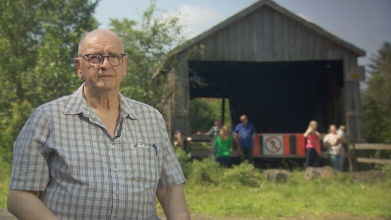 Ray Boucher poses for a photo with the covered bridge in the background.