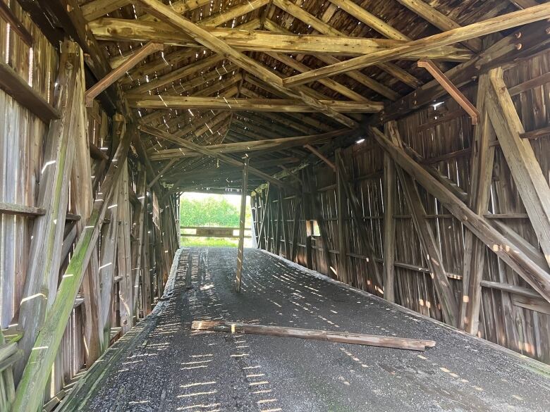 The inside of the covered bridge shows a sag in the floor and collapsed support beams.