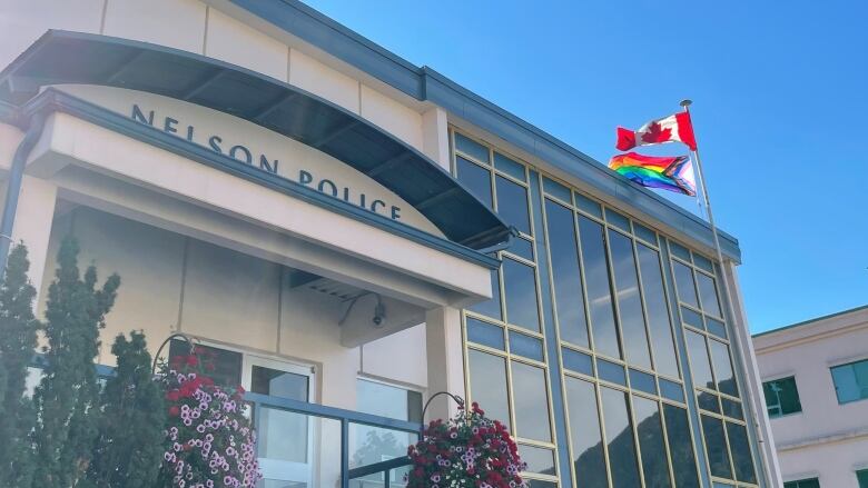 The exterior of a building with a sign that reads 'Nelson Police,' with a flag pole standing next to it.