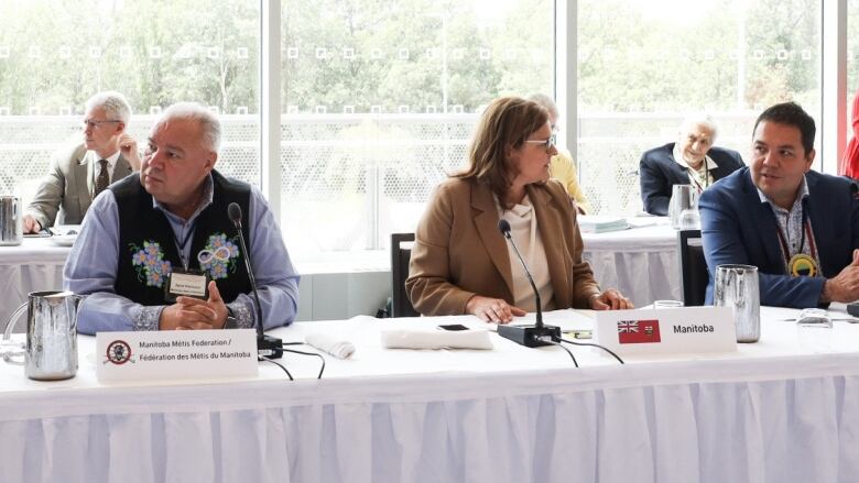 People sitting at two rows of tables are pictured.