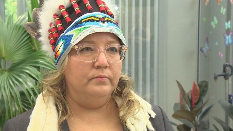 A woman wearing a headdress and glasses looks forward.