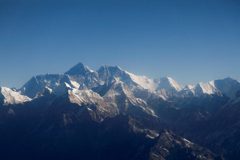 A rocky mountain range, with snow-capped peaks, is shown beneath a blue sky.